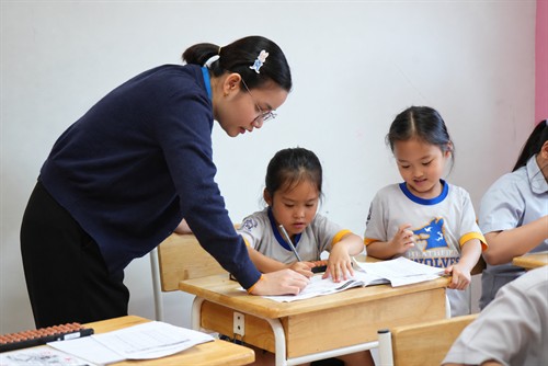 Teacher helping young students with classroom exercises