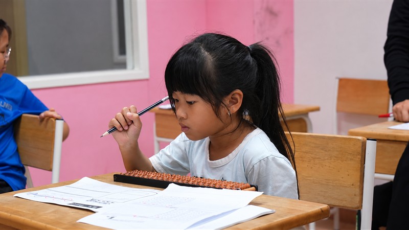 ນັກຮຽນຍິງກຳລັງຄິດໄລ່ດ້ວຍລູກຄິດ